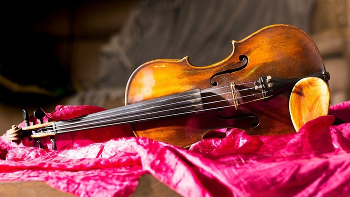 Ein Cello liegt auf einem roten Stoff.