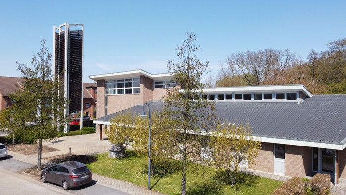 Modernes Gebäude mit Parkplatz und Bäumen im Vordergrund