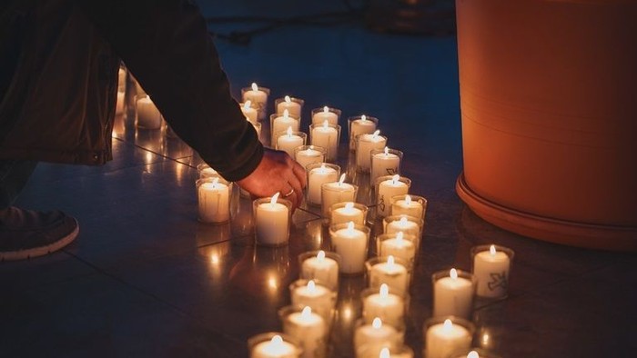 Person zündet Kerzen an, die in einem Kreis angeordnet sind