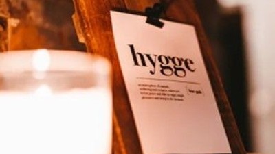 En lyseglade på en træskive med et papir med "hygge" skrevet på det.
