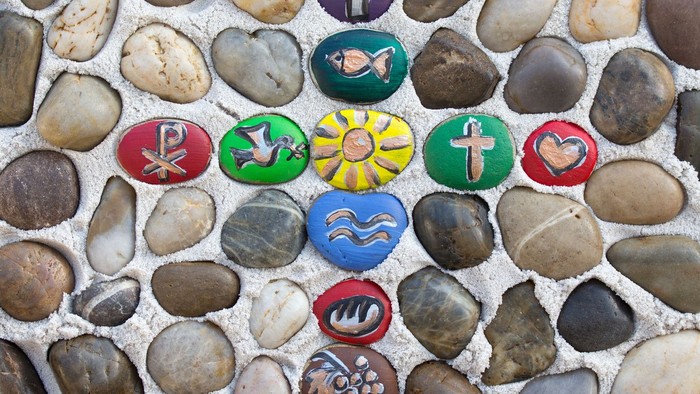 Bunte bemalte Steine inmitten von Kieseln angeordnet