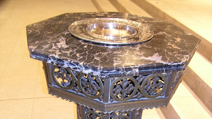 Elegante Marmor-Schrifttafel mit kunstvoller Schmiedeeisenbasis, wahrscheinlich für Taufzeremonien verwendet.