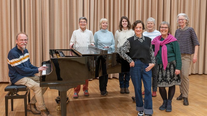 Gruppe von Menschen, die sich um ein Klavier versammelt posieren