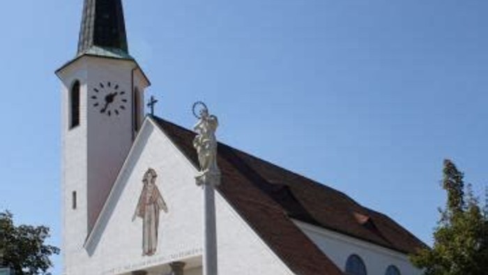 Weiße Kirche mit hohem Turm und Statue davor