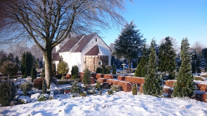 En snedækket have med en lille kapel og træer