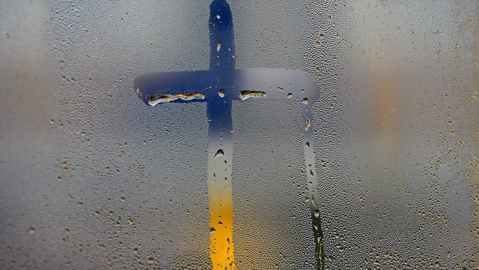 Kreuzform auf einem Fenster mit Wassertropfen.