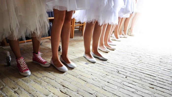 En rekke børn i hvidt tøj og forskellige sko står i en linje.