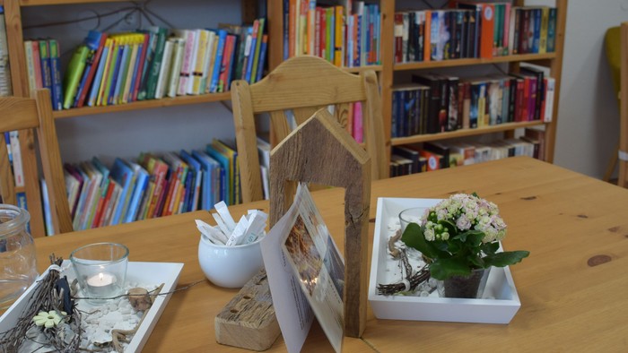 Holztresen mit Blumen und Schmuck, Bücherregal im Hintergrund