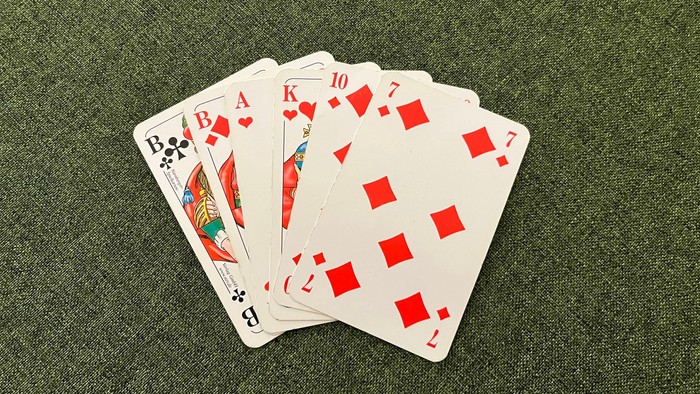 Fünf verstreute Karten mit roten Pik-Symbolen auf grünem Stoff