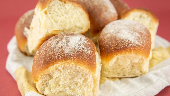 Friskbagte briocheboller drysset med flormelis i en kurv.
