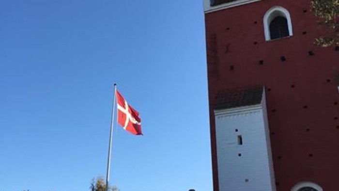 En rød bygning med en dansk flag på en klar blå himmel