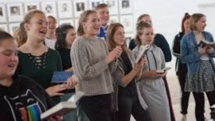 En gruppe af kvinder står i en sirkel og holder mobiltelefoner, måske under en workshop eller foredrag.