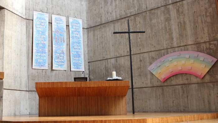 Die Kirche hat einen modernen Altar und ein farbiges Fenster.