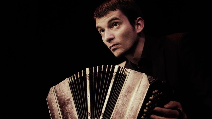 Ein junger Mann spielt Akkordeon im Dunklen.