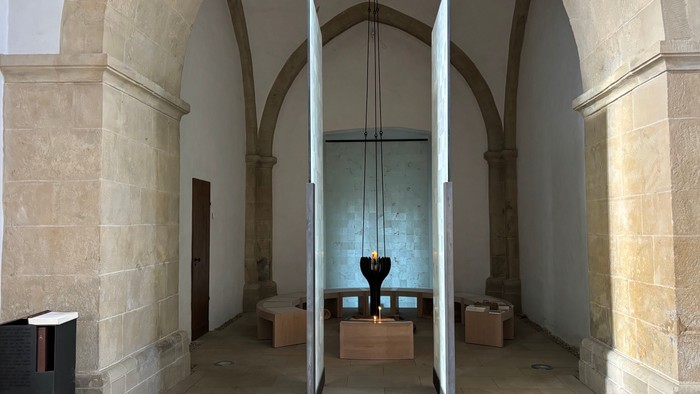 Auf dem Bild ist der Raum der Stille der Christuskirche zu sehen. In der Mitte ist eine Kerze