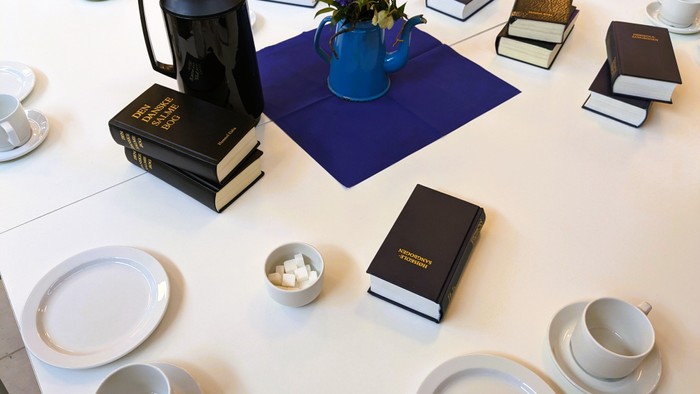 Bord med tepoter, tekanne, bøger og blomster.