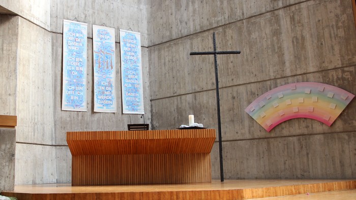 Die Kirche hat einen modernen Altar und ein farbiges Fenster.