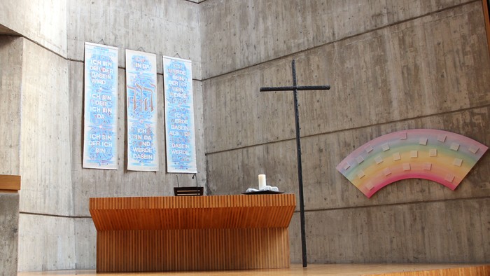 Die Kirche hat einen modernen Altar und ein farbiges Fenster.