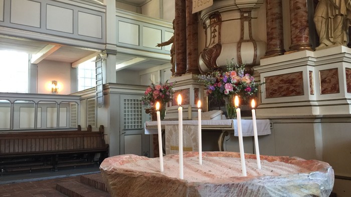In der Kirche stehen Kerzen und Blumen auf einem Tisch.