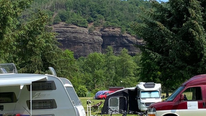 Ein Campingplatz mit Wohnwagen und Fahrrädern vor einem bewaldeten Hügel.