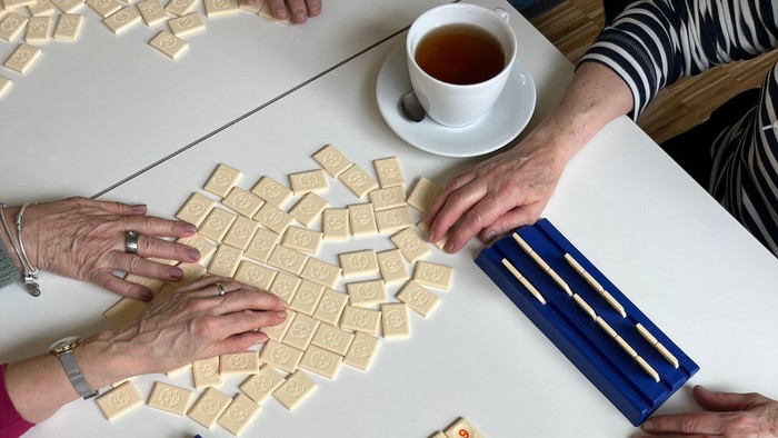 Eine Gruppe von Menschen spielt Scrabble bei einer Tasse Tee