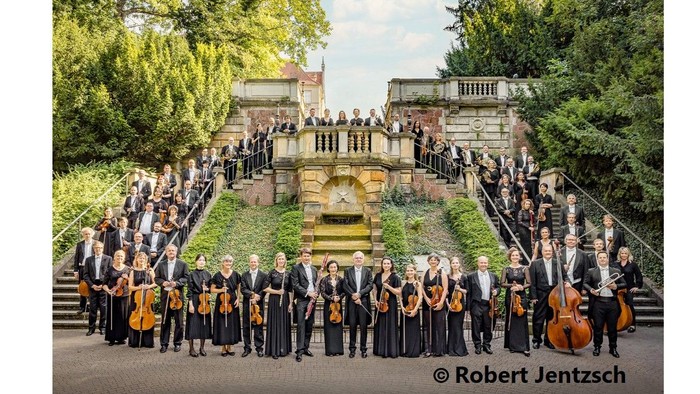 Große Gruppe von Musiker:innen, die sich im Freien mit Instrumenten fotografieren lassen.
