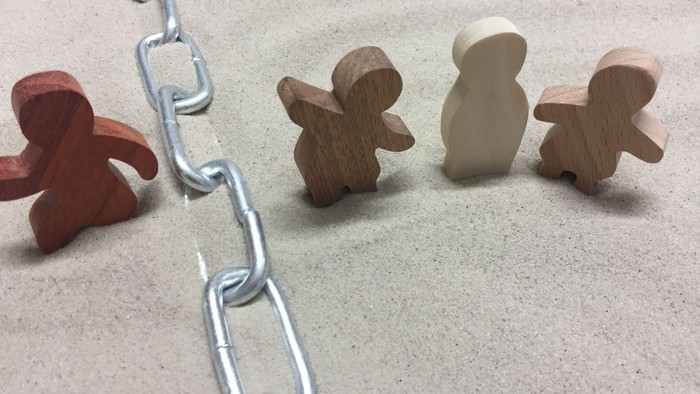 Holzfiguren, die durch eine Metallkettenverbindung auf einer hellen Oberfläche verbunden sind.