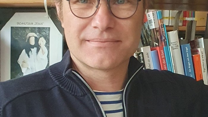 Mann mit Brille vor Bücherregal