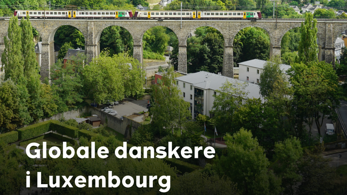 Et tog krydser en historisk bro i Luxembourg omgivet af frodig grønne omgivelser med bybillede i baggrunden den 29. april.