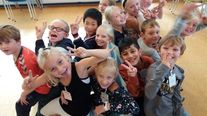 En gruppe af glade børn og en voksne kvinde i en klassesal