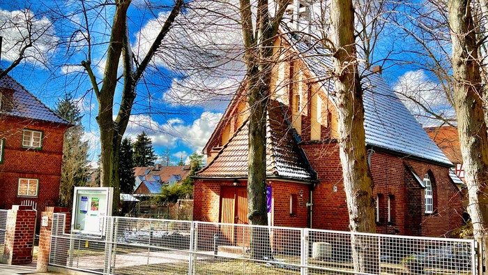 Ein rotes Backsteingebäude mit blauen Dächern und kahlen Bäumen im Vordergrund