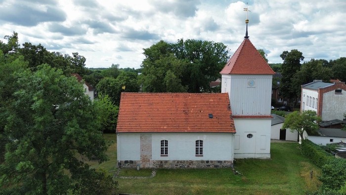 Weißes Haus mit rotem Dach und Turm in ländlicher Umgebung