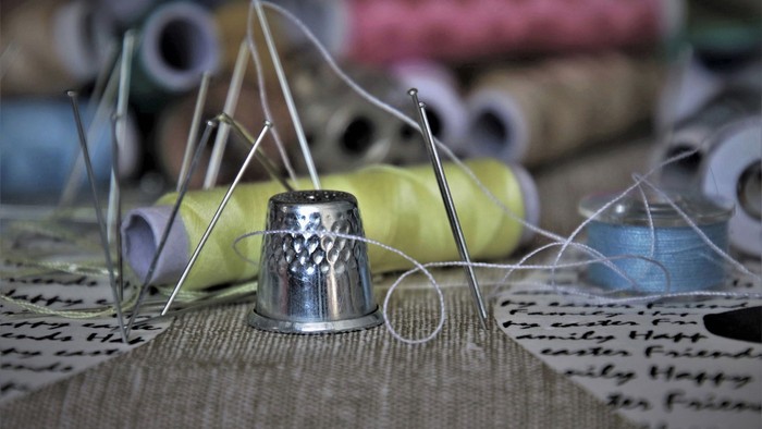 Näheutensilien wie Nadeln, Faden und Nadelkissen auf einem Tisch