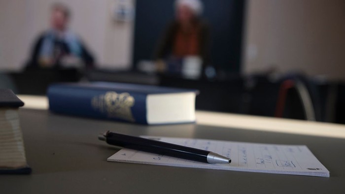 Notesblok med højskolesangbog og mennesker i baggrunden