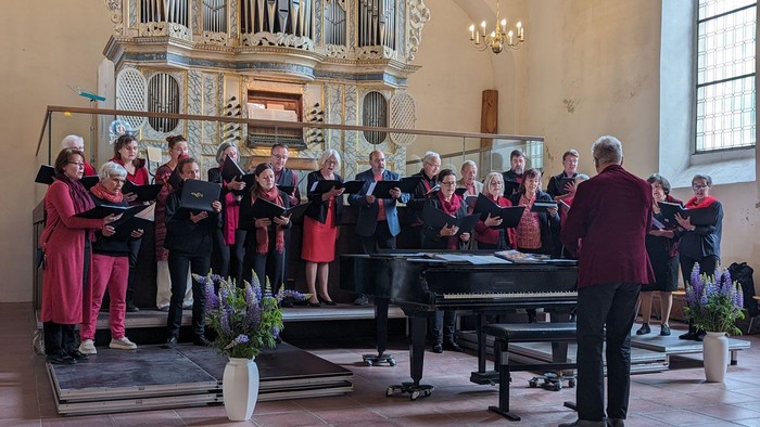 Ein Chor in roter und schwarzer Kleidung singt in der Kirche in Bad Belzig.