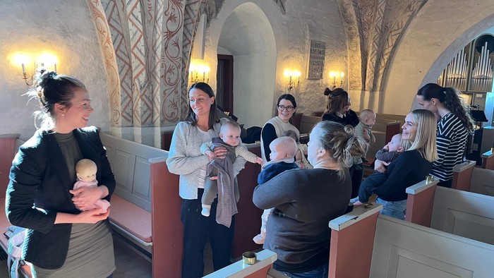 Forældre med deres babyer står i kirken og synger sange og remser