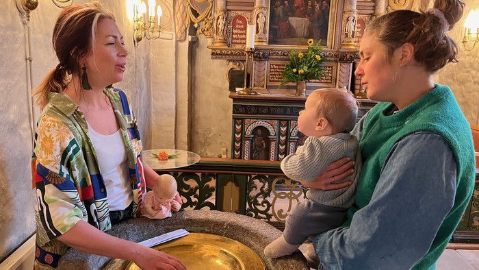 Mor med baby synger ved døbefonten