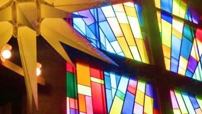 Leuchtende Papiersterne vor buntem Kirchenfenster