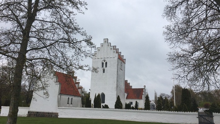 Et hvidt slot med røde tag og klokketårn i snødekt landskab