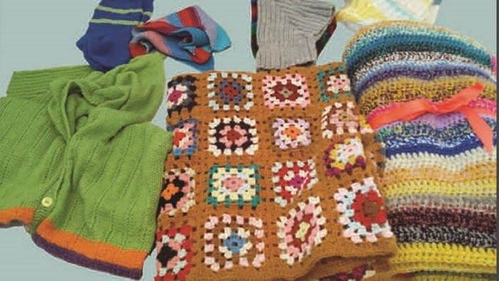 Billedet viser en samling af håndarbejdede skarves og skjorter i forskellige farver og mønstre.