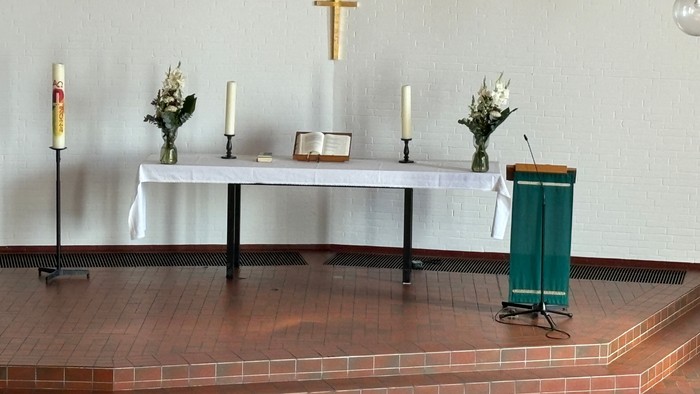 Ein Altar in einer Kirche mit Kerzen, Blumen und Kreuz