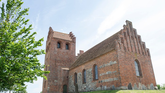 Det er en gammel murstenskirke med to tårne og bjælkerøfter.