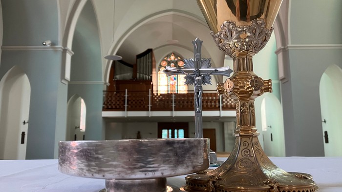 Goldene Kelche und Kreuz auf weißem Tisch in Kirche