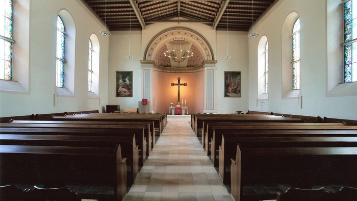 Leere Kirche mit Holzbänken und Altarraum
