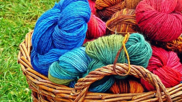 Ein Korb gefüllt mit bunter Wolle auf dem Gras