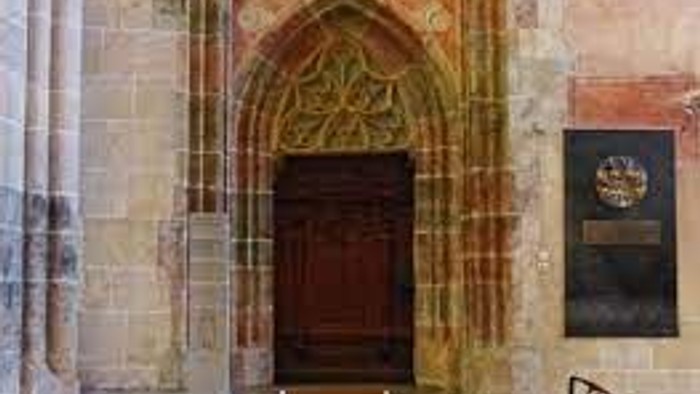 Das Bild zeigt einen alten, verzierten Türbogen in einem historischen Gebäude.