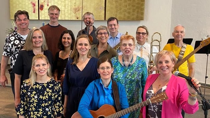 Ein großer Musikgruppe posiert vor einem goldenen Gemälde