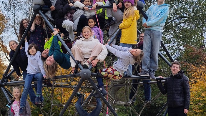 Eine lebhafte Gruppe posiert kreativ auf einer großen Fahrradskulptur im Freien in einem Park.