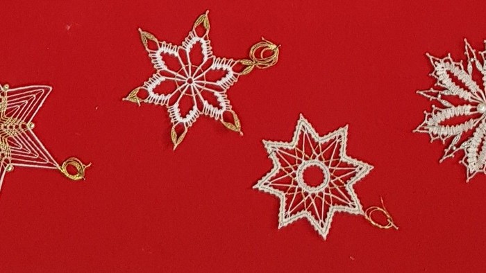 Vier goldene Schneeflocken-Dekorationen auf rotem Hintergrund