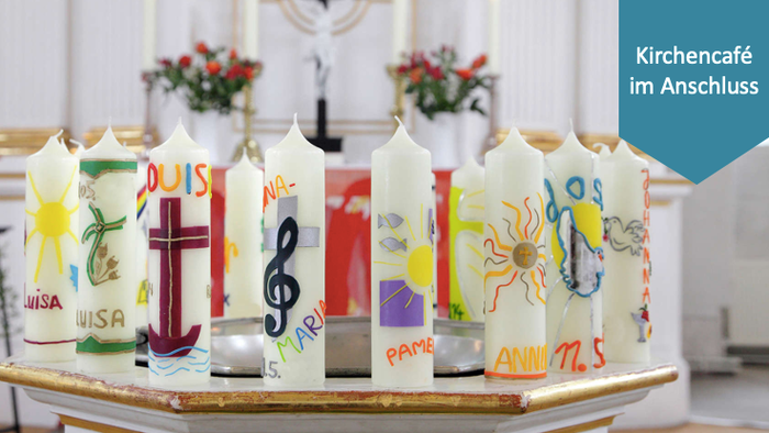 Verzierte Kerzen, die in einem Kreis angeordnet sind, mit verschiedenen internationalen Symbolen und Ländernamen in einem Kirchen-Café.